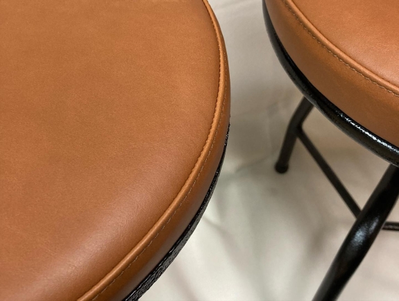 Close up ovenfra af ombetrækning af to barstole i brun og sort. 